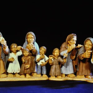 Tonskulptur zeigt stilisiert Gemeinschaft aus Frauen und Kindern vor dunklem Hintergrund.