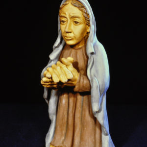Eine bemalte Tonfigur einer Frau mit Schleier und gefalteten Händen.