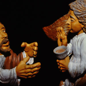 Eine farbige Tonskulptur zeigt dramatisch eine biblische Szene mit zwei Figuren.