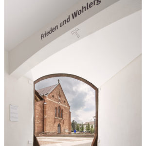 Ein Durchgang zeigt eine rote Kirche mit Kreuz und den Schriftzug „Frieden und Wohlergehen“.