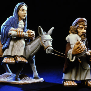 Die heilige Familie mit Maria, Josef und Jesus steht vor schwarzem Hintergrund.