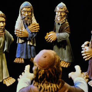 Tonfiguren, vermutlich eine Krippenszene, werden durch Licht und dunklen Hintergrund betont.