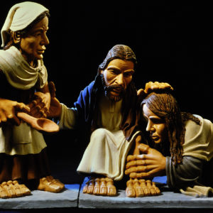 Eine Skulpturengruppe zeigt eine biblische Szene mit kniender Frau und segnendem Jesus.