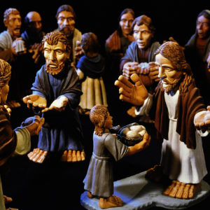 Tonfiguren zeigen Jesus, der ein Kind segnet, umgeben von biblischen Gestalten.