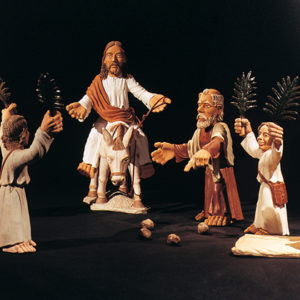 Tonskulptur zeigt Jesu Einzug in Jerusalem mit stilisierten Figuren und Palmenzweigen.