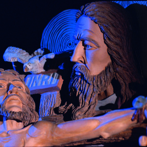 Eine Tonskulptur zeigt detailreich die Kreuzigung Jesu, betont durch Licht und dunkle Töne.