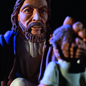 Eine farbige Tonskulptur zeigt eine religiöse Szene mit einer zentralen männlichen Figur in Roben.