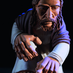 Jesus Christus kniet, weist mit ausgestreckten Händen und schreibt mit Finger in den Sand.