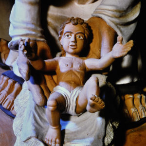 Eine Skulptur zeigt Madonna und Jesuskind, betont durch Licht und dunklen Hintergrund.