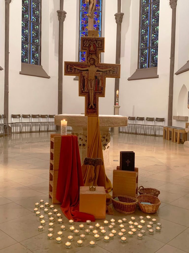 Kreuz von San Damiano im Chorraum der Kirche mit brennenden Kerzen