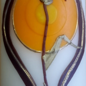 Eine Kerze zeigt eine stilisierte Blüte vor sonnenartigem Kreis mit spiritueller Symbolik.