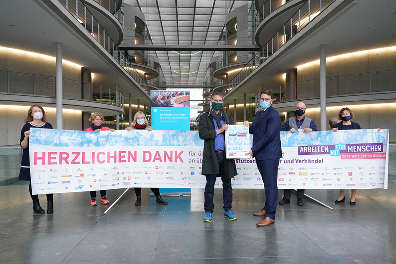 Eine Gruppe maskierter Personen dankt Organisationen für ihre Arbeit mit Menschen.